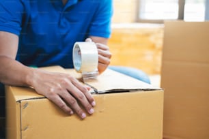 Small online business owner packing in the cardbox. Young man preparing parcel box of product for delivery to customer.