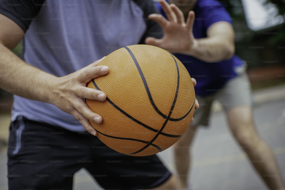 ボールを持つ手の接写。公園でバスケッ��トボールをする友達。
