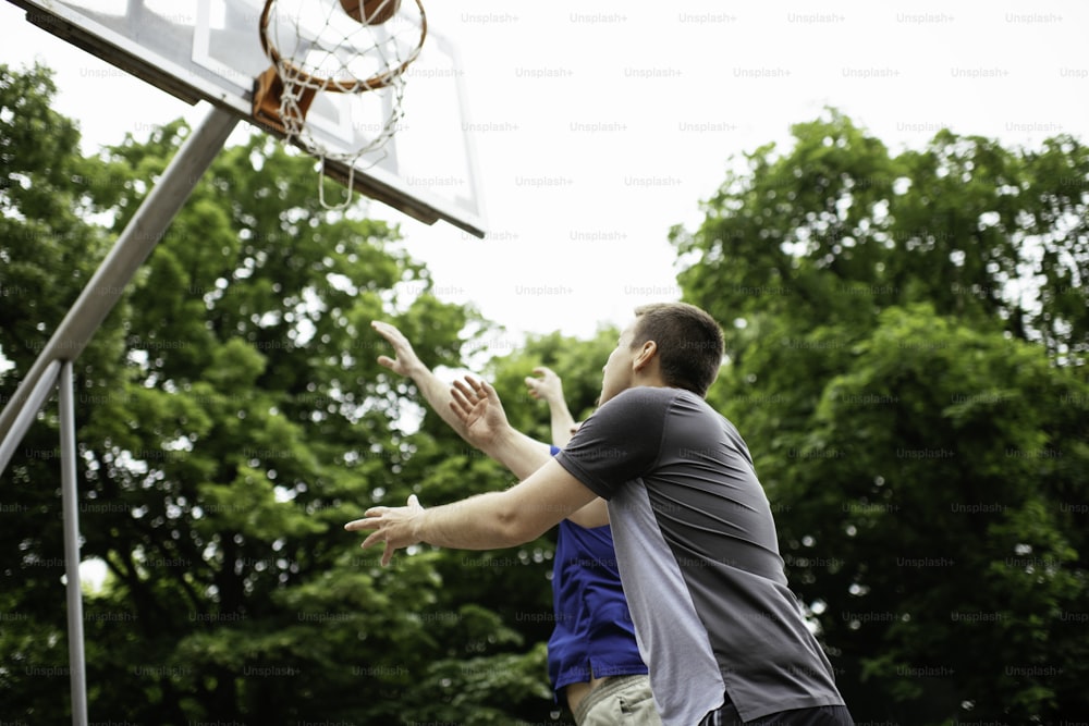 Two friends playing basketball on court outdoors and having fun.