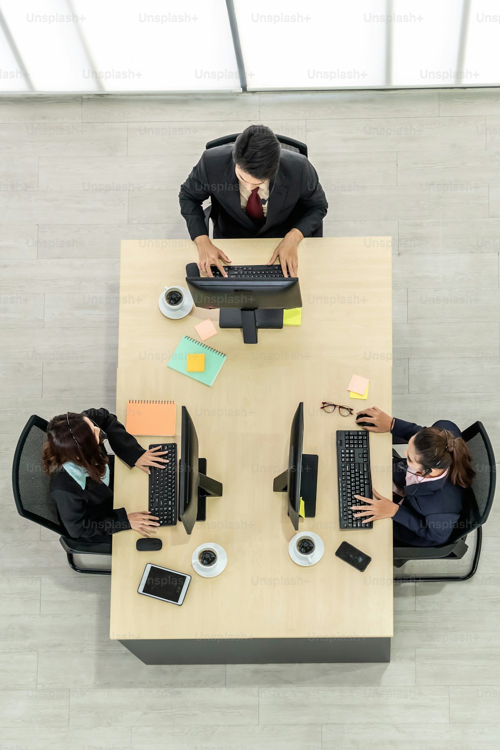 Des gens d’affaires portant un casque d’écoute de dessus au bureau travaillant avec un ordinateur pour soutenir un client ou un collègue à distance. Centre d’appels, service d’agent de télémarketing par téléphone ou vidéoconférence.