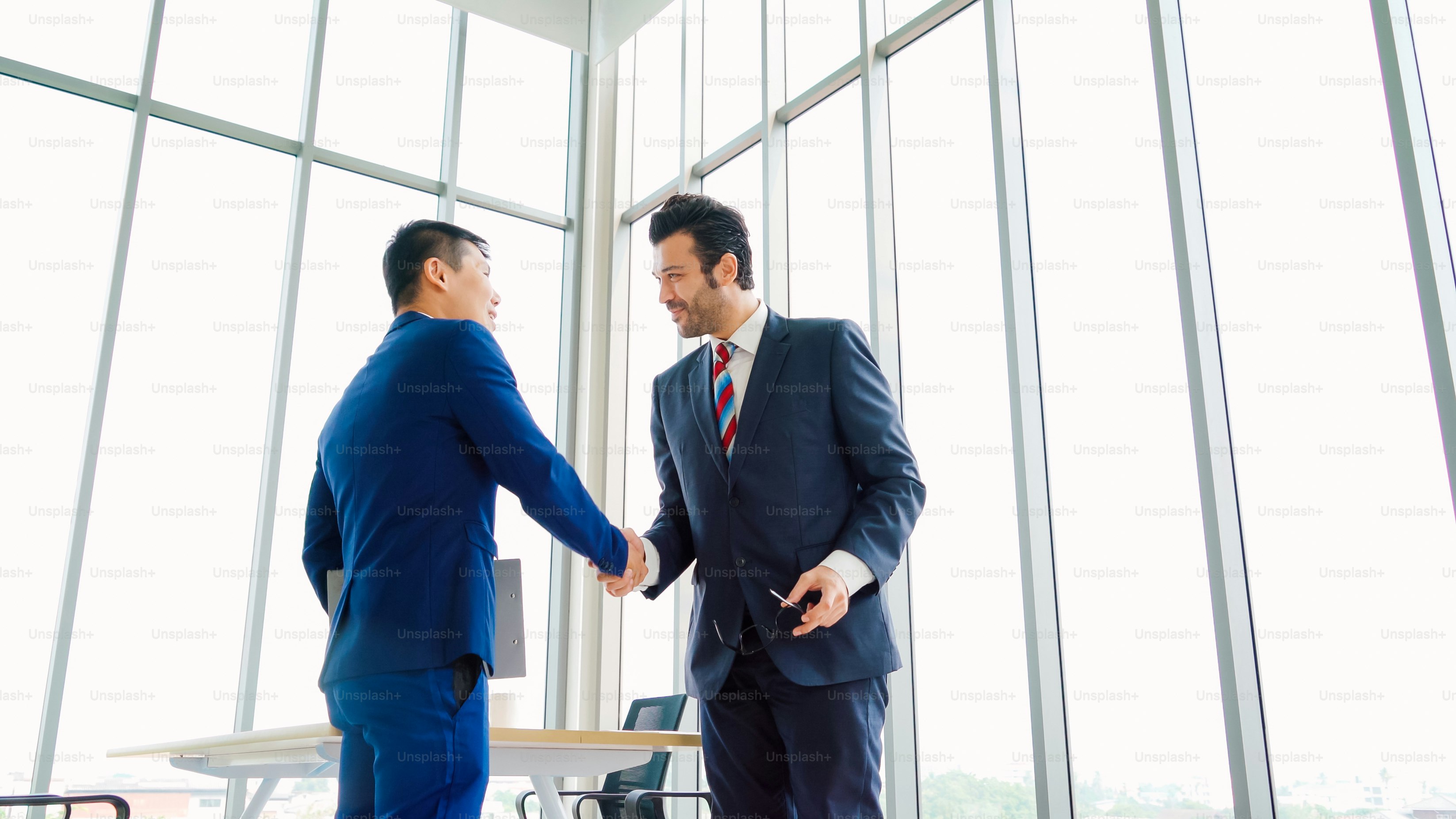 Business people handshake in corporate office showing professional agreement on a financial deal contract.