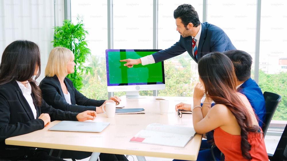 Gente de negocios en la sala de conferencias con pantalla verde chroma key TV o computadora en la mesa de la oficina. Grupo diverso de hombres y mujeres de negocios en reunión en videoconferencia.
