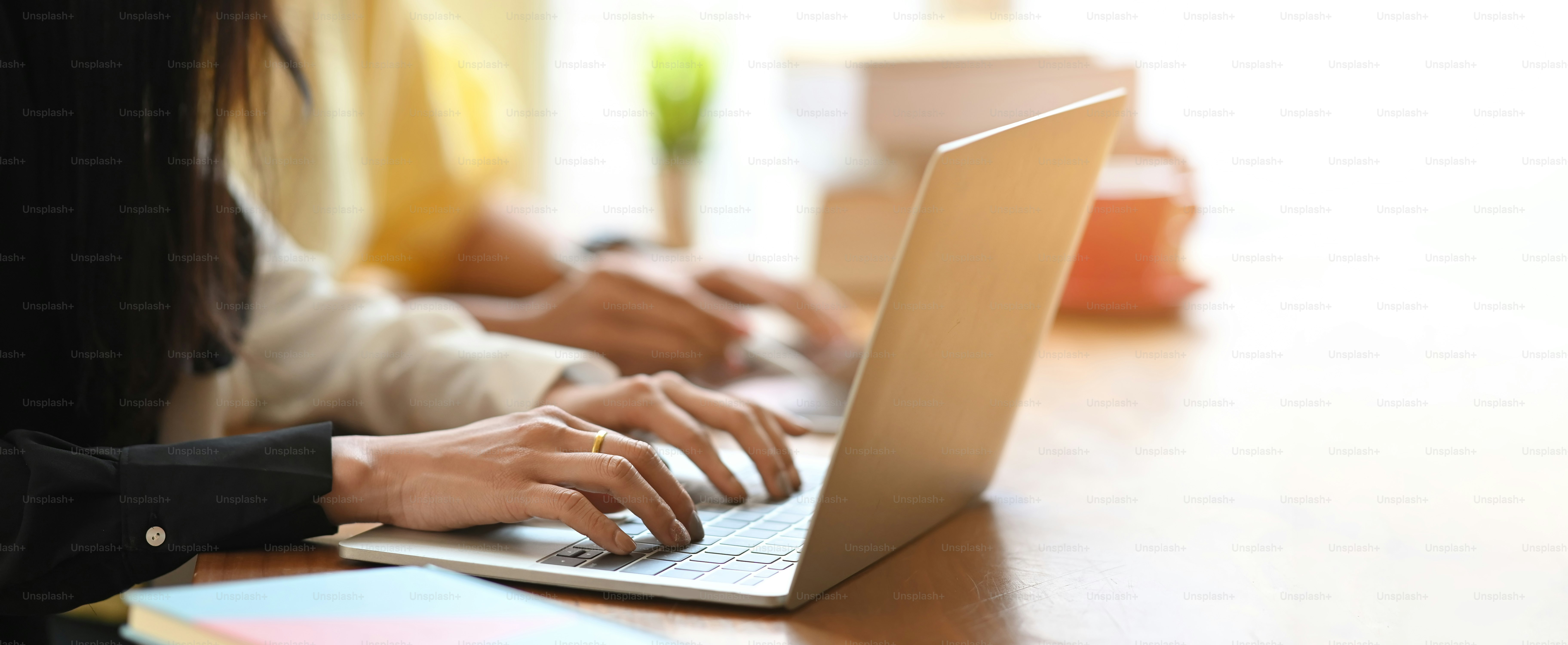 Businesswomen are working together by using a computer laptop and tablet at the wooden working desk.