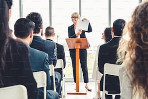 Group of business people meeting in a seminar conference . Audience listening to instructor in employee education training session . Office worker community summit forum with expert speaker .