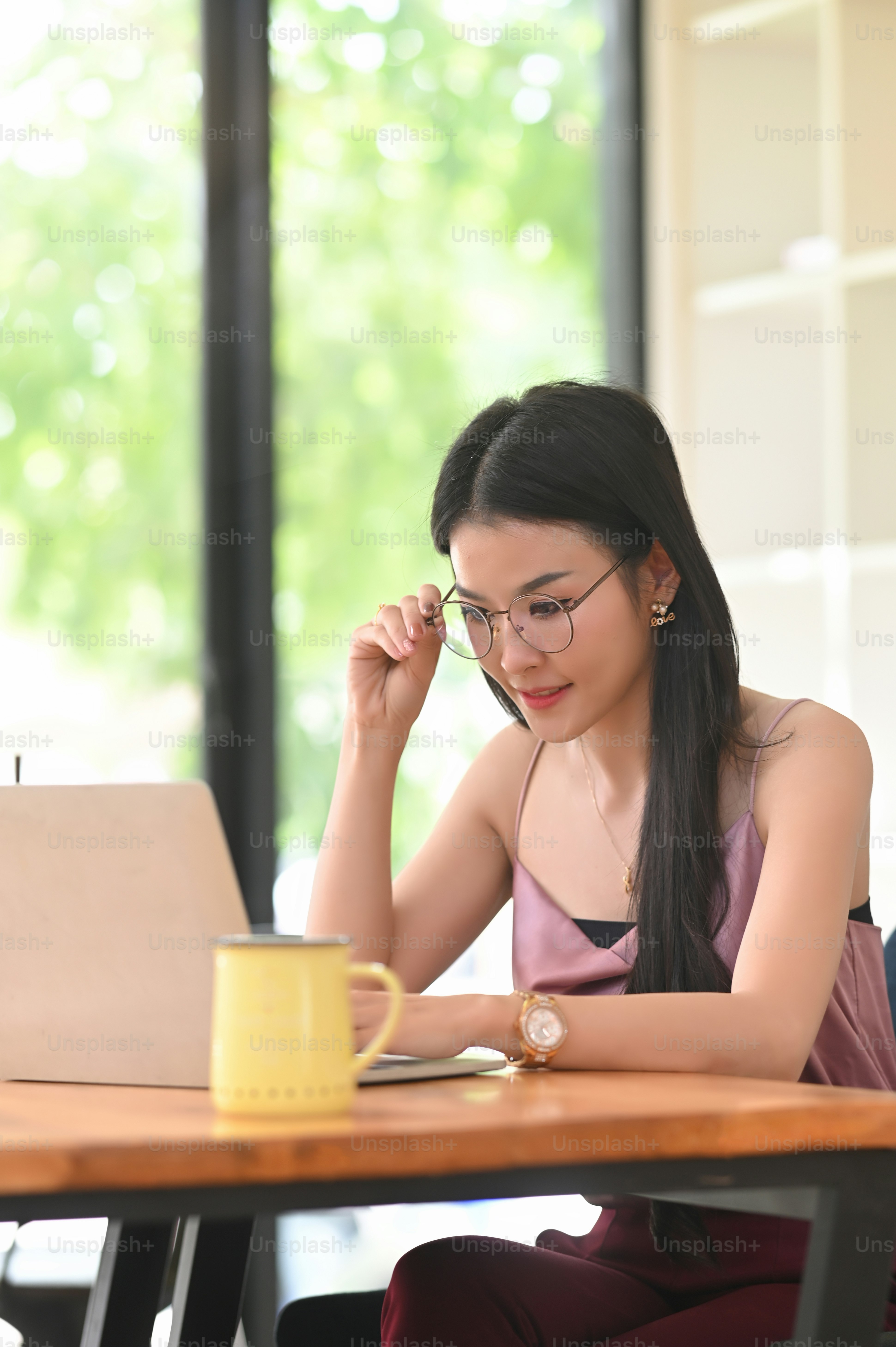A woman with glasses is using a computer laptop while sittin