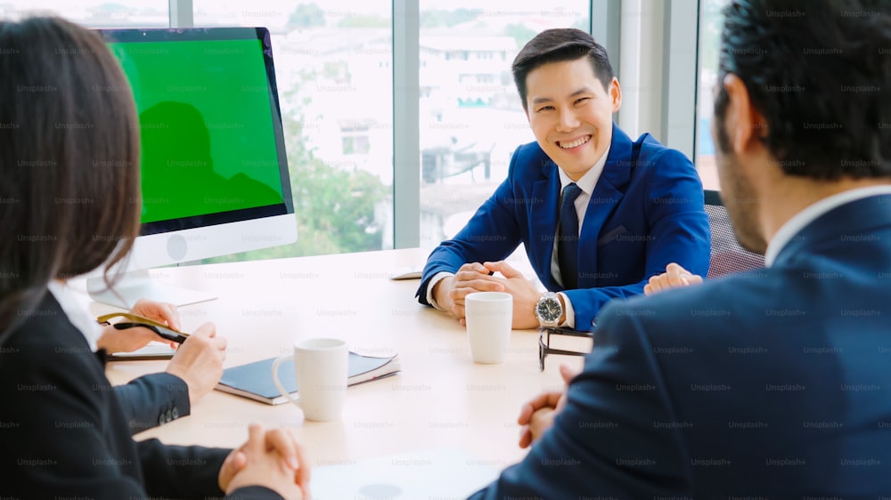 Gente de negocios en la sala de conferencias con pantalla verde chroma key TV o computadora en la mesa de la oficina. Grupo diverso de hombres y mujeres de negocios en reunión en videoconferencia.