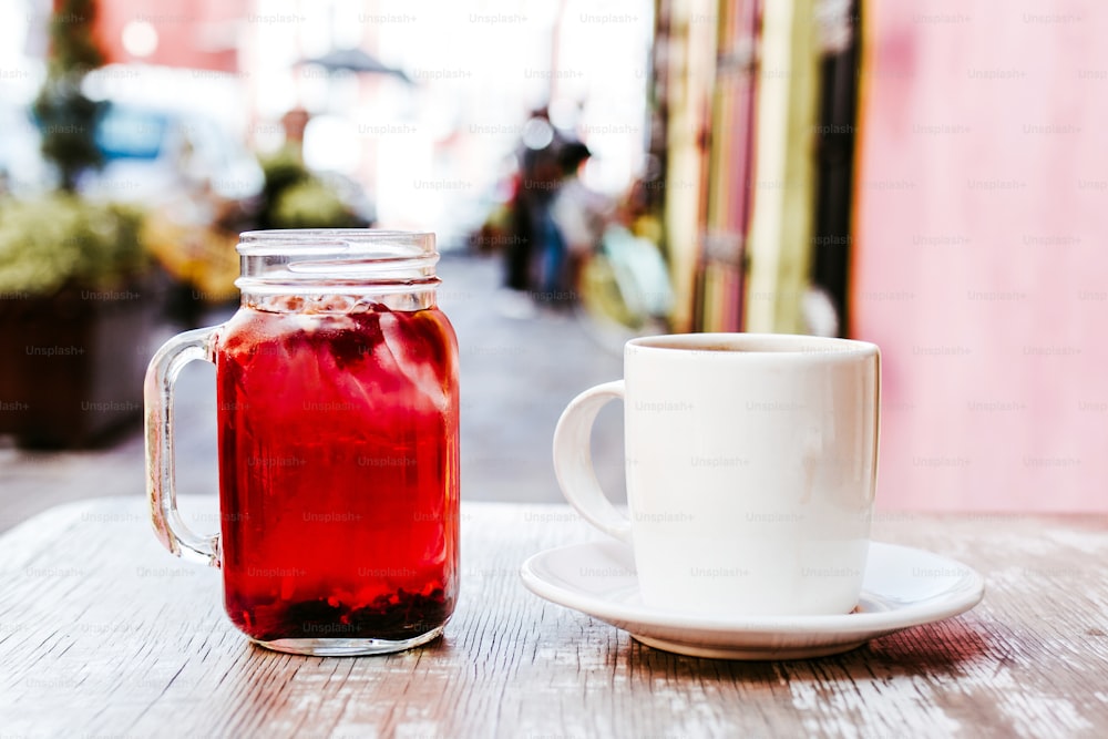 taza de café y tisana o taza de té de hierbas rojas en una mesa al aire libre en una casa de té en la calle