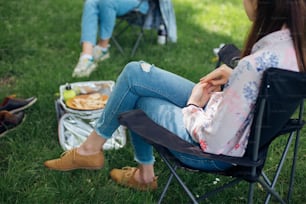 Soziale Distanzierung. Kleine Gruppe junger Frauen, die sich beim Picknick mit sozialer Distanz im Sommerpark unterhalten. Gemeinsame Freizeitgestaltung in neuer Normalität, sichere Zusammenkünfte