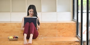 A woman is relaxing with a computer laptop while sitting on a wooden bench.