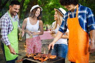 Group of friends having outdoor barbecue party and fun together