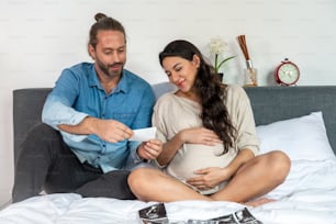 Happy Caucasian pregnant woman looking ultrasound baby picture together with her husband