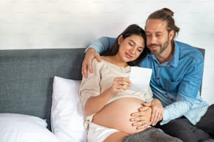 Glückliche kaukasische schwangere Frau, die zusammen mit ihrem Ehemann Ultraschall-Babybild sucht