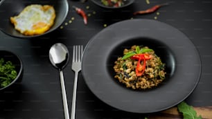 Thai traditional food, Stir fried minced pork with basil (Pad ka prao), fried egg and chili fish sauce serving on black ceramic plates in Thai restaurant