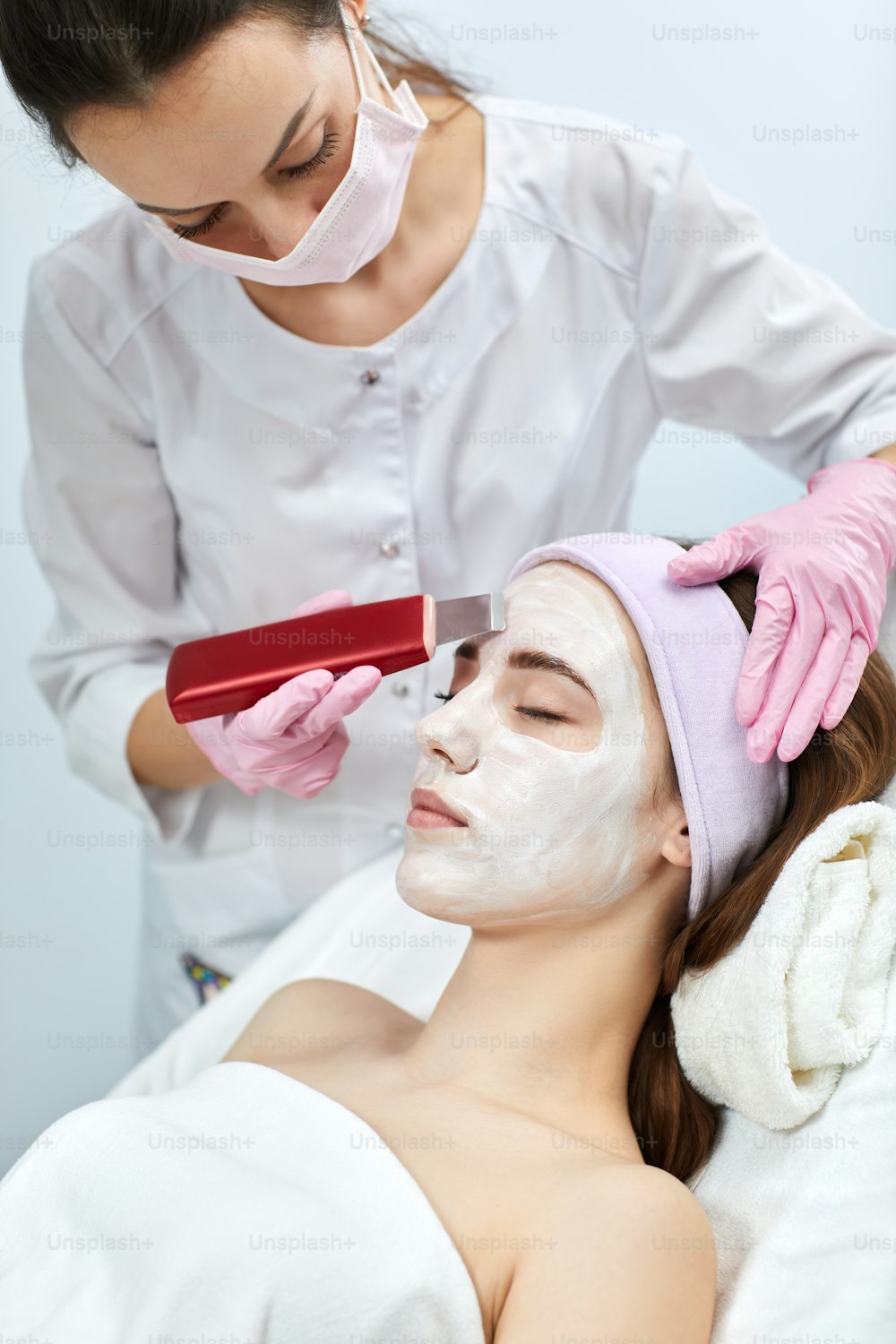 beautician makes procedure ultrasound cleansing of woman's face , facial peeling. ultrasonic treatment for skin rejuvenation