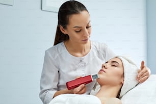visage de la femme pendant la procédure de nettoyage par ultrasons, peeling du visage. Traitement par ultrasons pour le rajeunissement de la peau