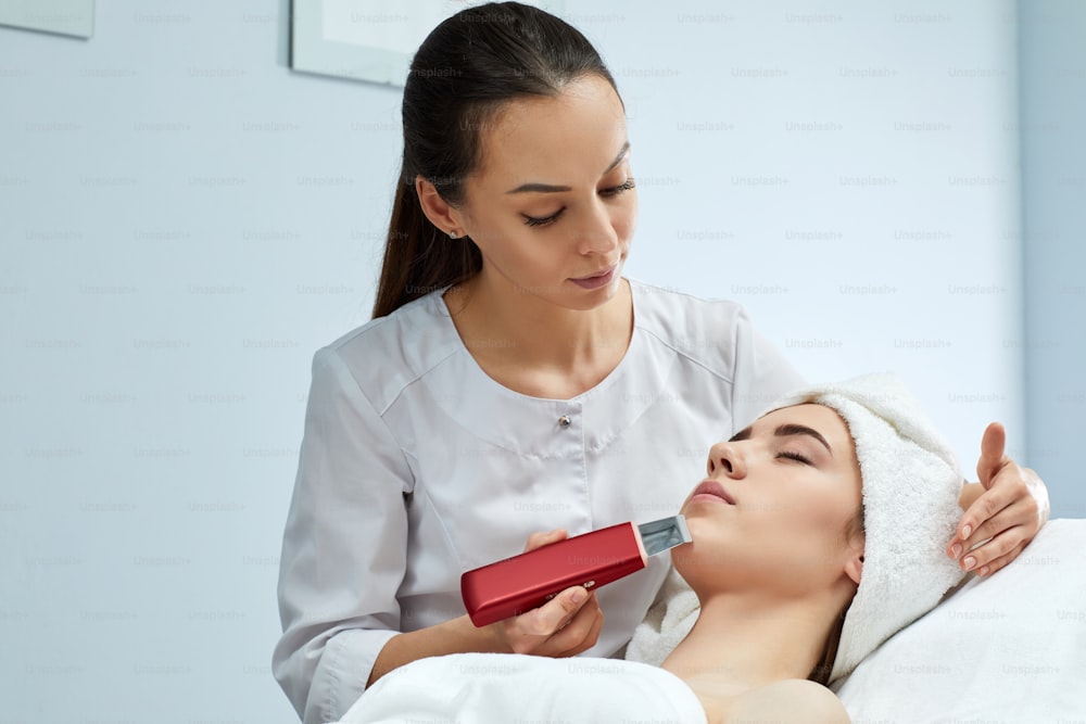 rosto da mulher durante o procedimento de limpeza de ultrassom, peeling facial. tratamento ultra-sônico para rejuvenescimento da pele