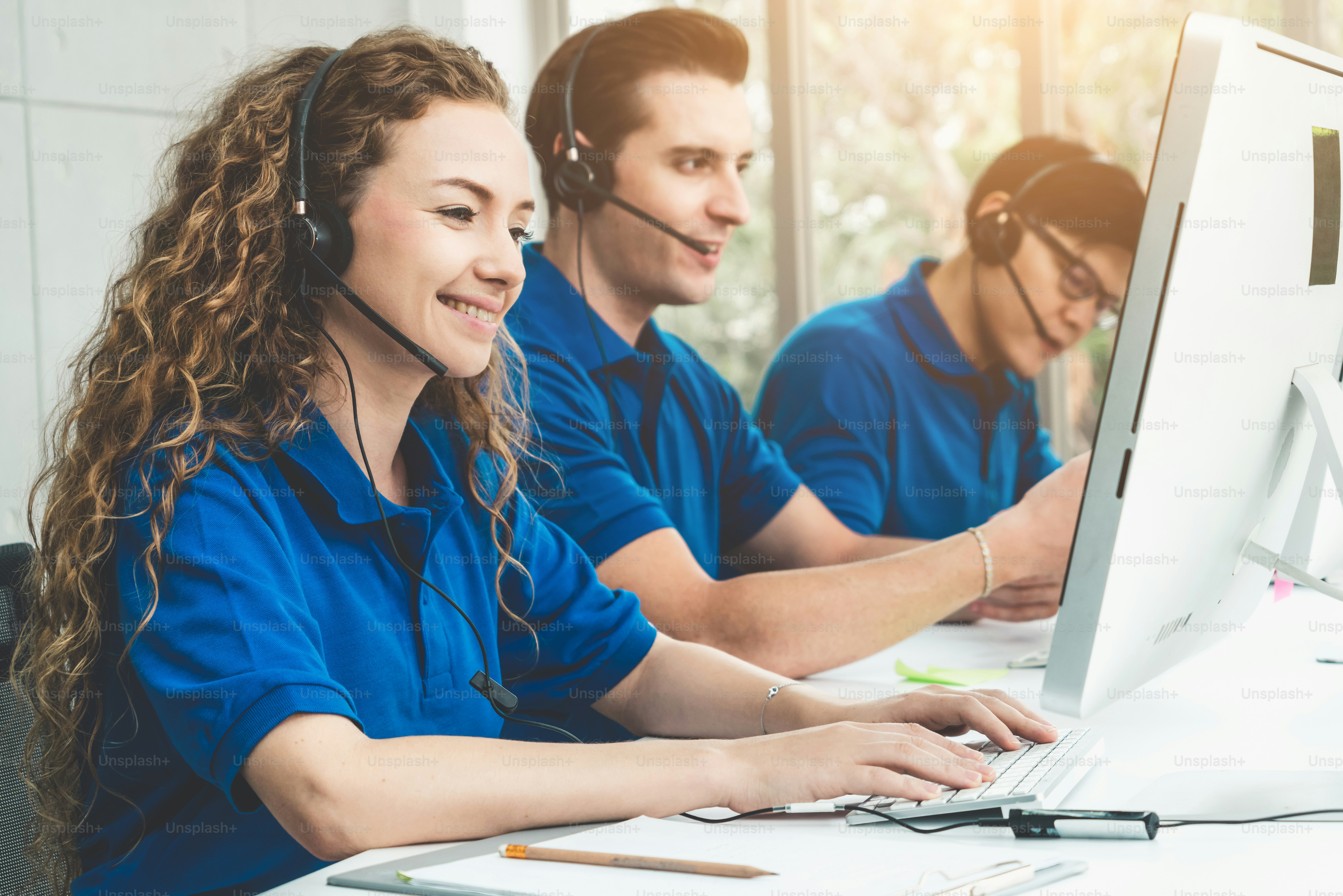 Geschäftsleute, die ein Headset tragen, arbeiten im Büro, um entfernte Kunden oder Kollegen zu unterstützen. Call-Center, Telemarketing, Kundendienstmitarbeiter bieten Service auf Telefon-Videokonferenz-Anruf.