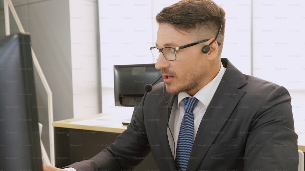 Business people wearing headset working in office to support remote customer or colleague. Call center, telemarketing, customer support agent provide service on telephone video conference call.