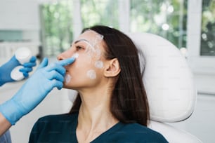 Beautiful and young blonde woman receiving beauty treatment at medical clinic. Brightly lit close up shot.