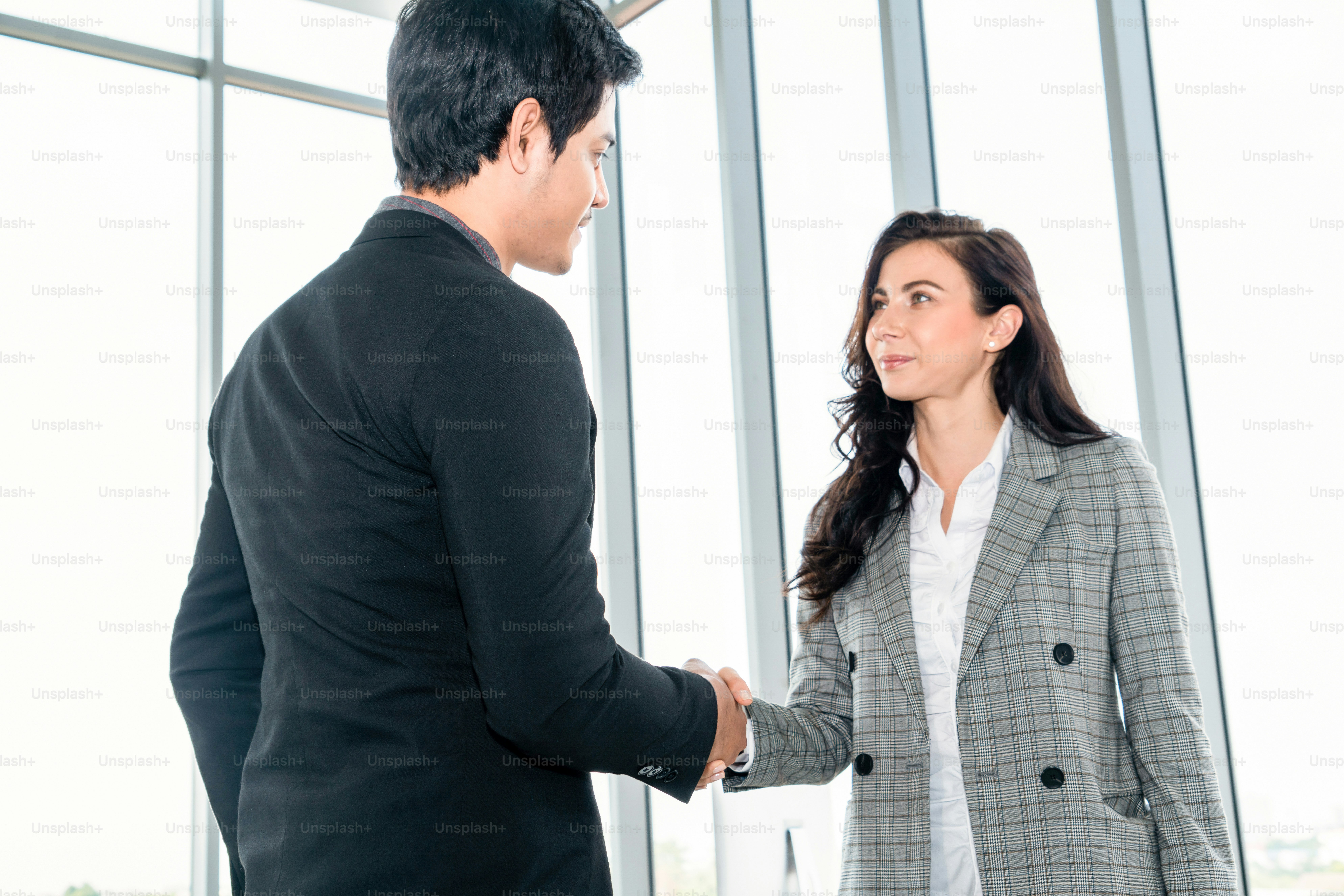 Business people handshake in corporate office showing professional agreement on a financial deal contract.