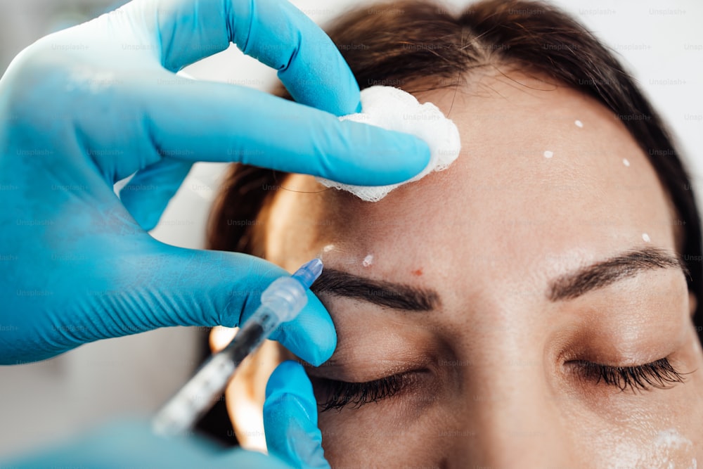 Attractive blond woman is getting a rejuvenating facial injections at beauty clinic. The expert beautician is filling female wrinkles by botulinum.