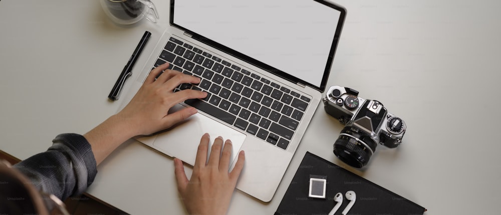 Overhead-Aufnahme einer Fotografin bei der Arbeit an einem modernen Büroschreibtisch mit Mock-up-Tablet, Kamera und Zubehör
