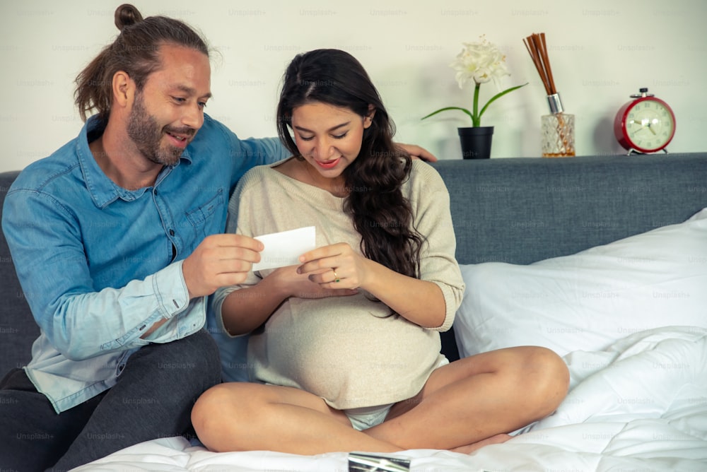 Mujer embarazada caucásica feliz que busca la imagen del bebé de ultrasonido junto con su esposo