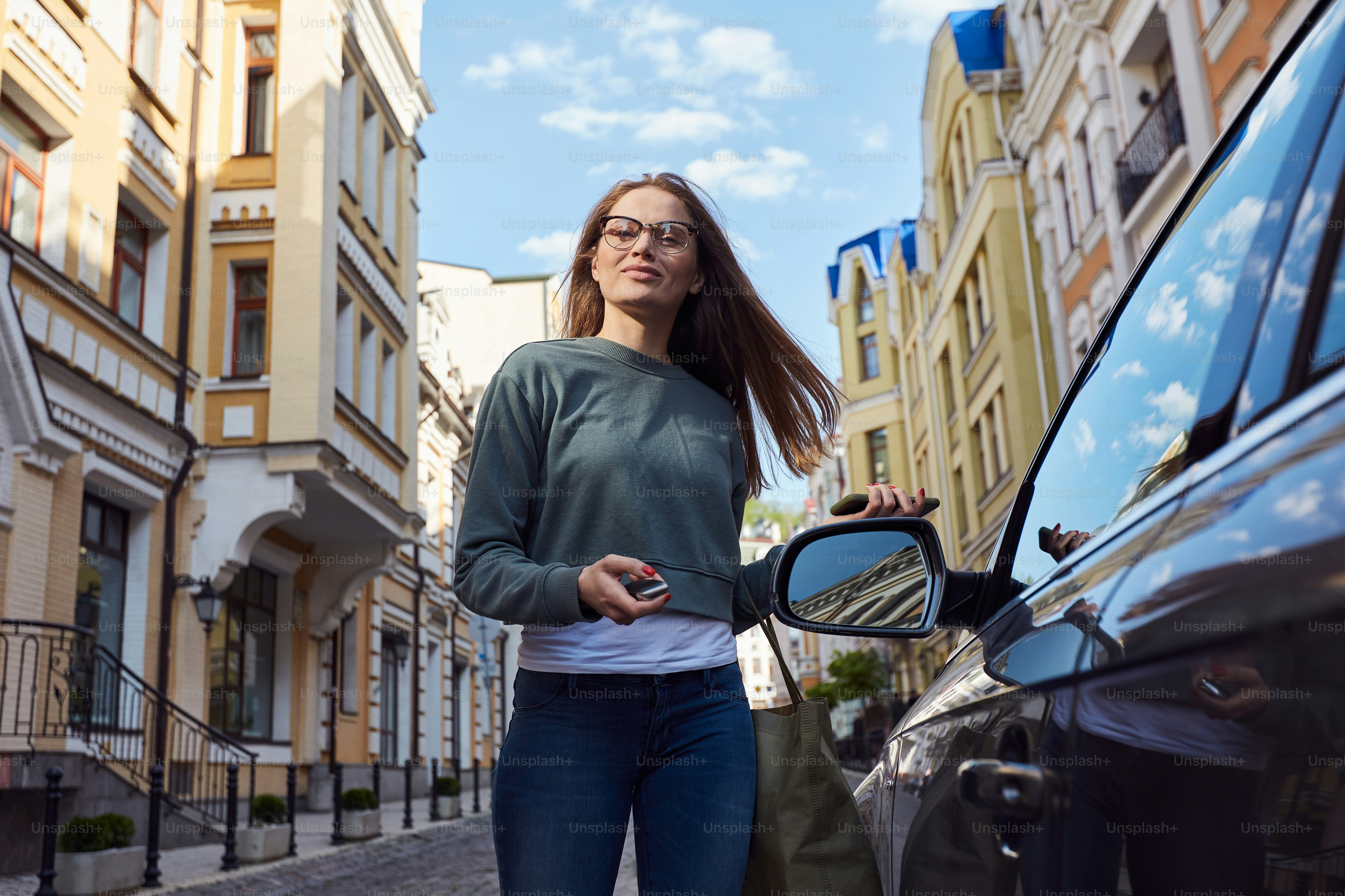 Confident casually dressed woman unlocking her automobile with a help of security fob