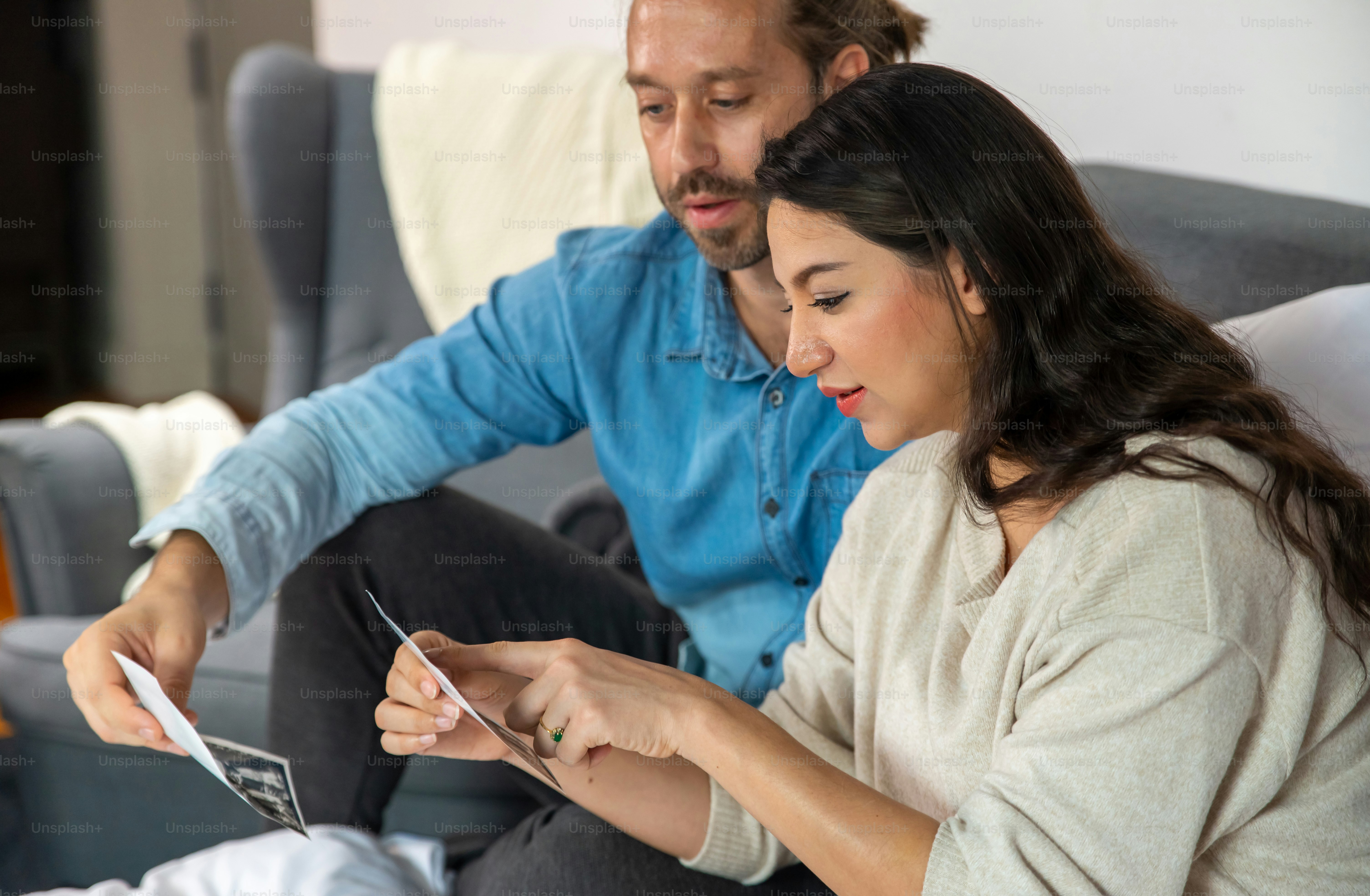 Happy Caucasian pregnant woman looking ultrasound baby picture together with her husband