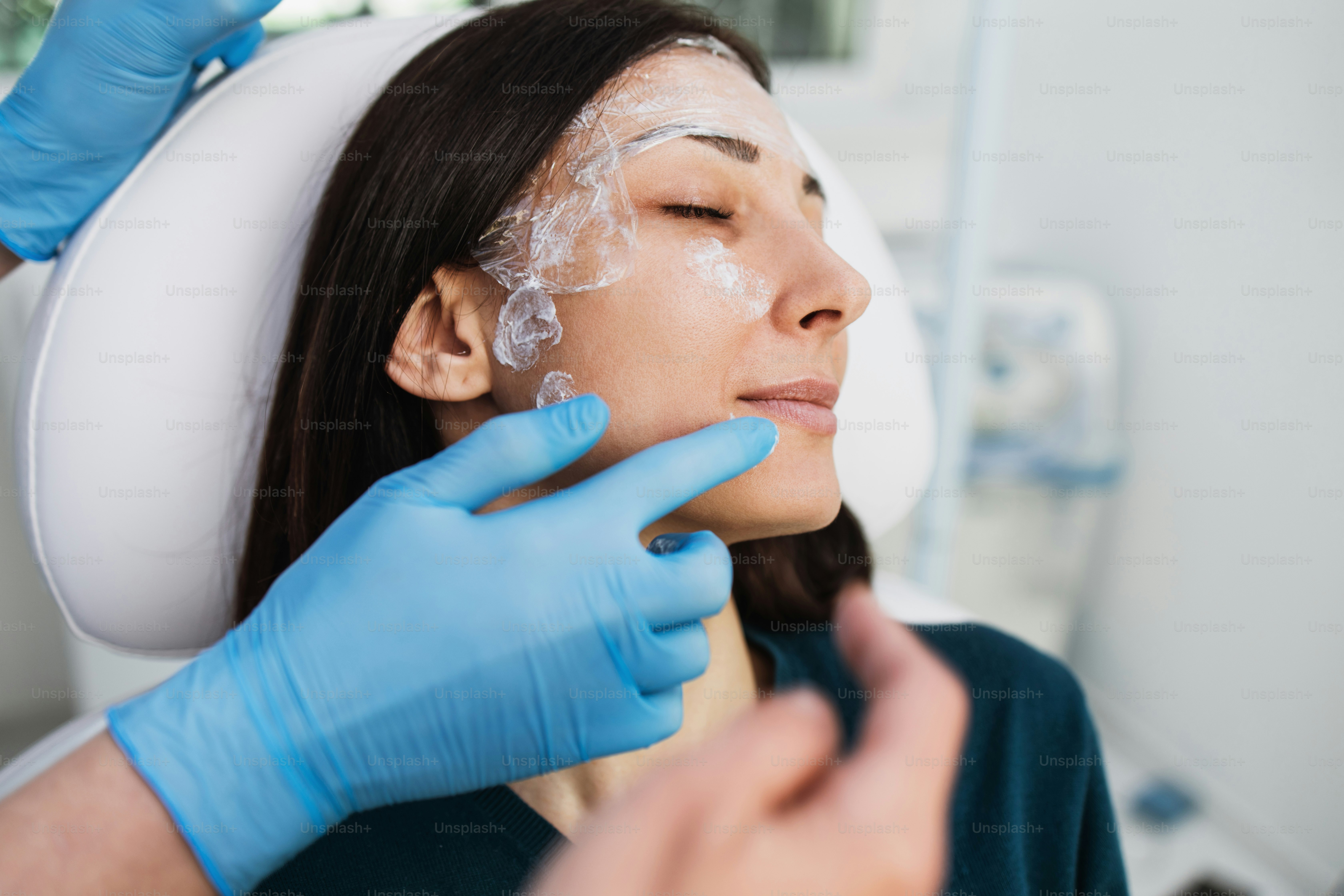Beautiful and young blonde woman receiving beauty treatment at medical clinic. Brightly lit close up shot.