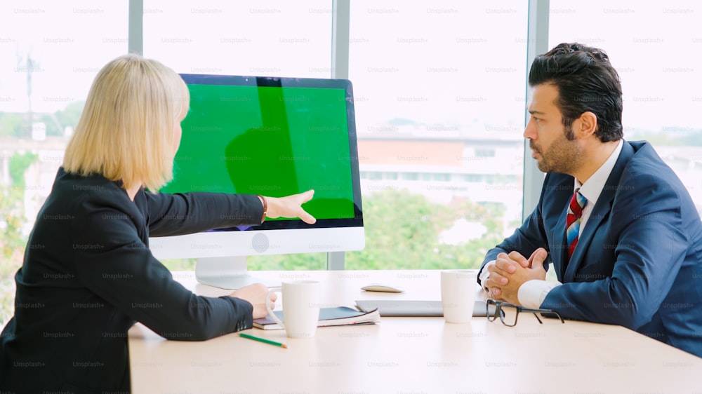 Business people in the conference room with green screen chroma key TV or computer on the office table. Diverse group of businessman and businesswoman in meeting on video conference call .