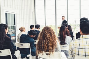 Group of business people meeting in a seminar conference . Audience listening to instructor in employee education training session . Office worker community summit forum with expert speaker .