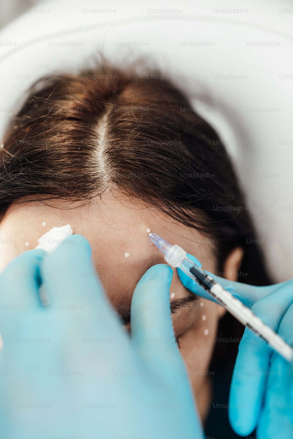 Attractive blond woman is getting a rejuvenating facial injections at beauty clinic. The expert beautician is filling female wrinkles by botulinum.