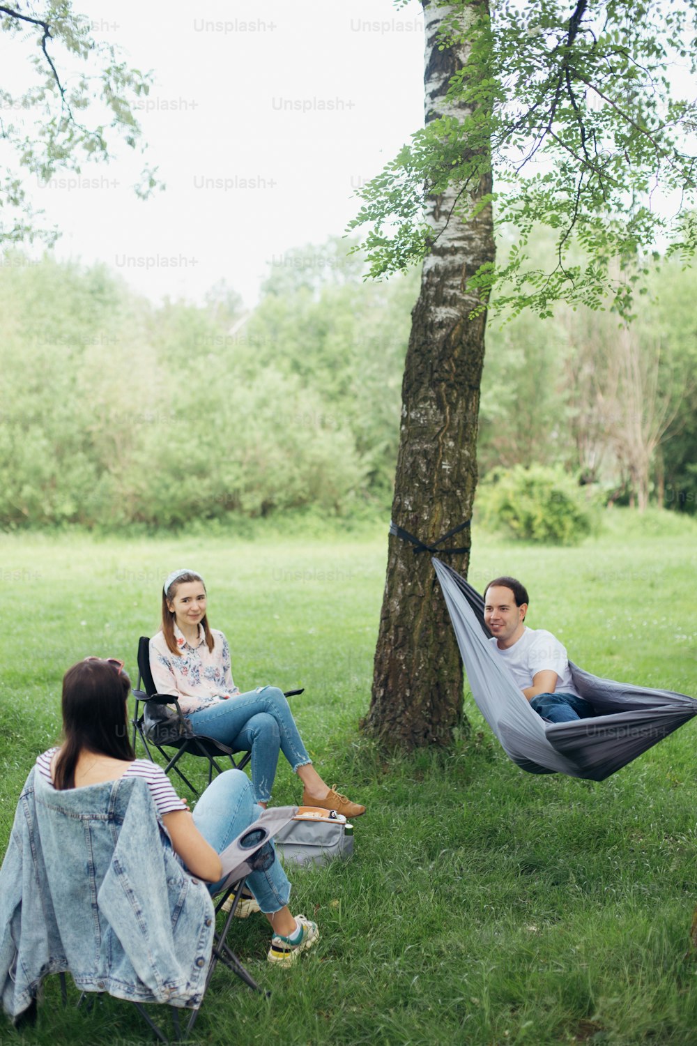 Social distancing. Small group of people enjoying conversation at picnic with social distance in summer park. Leisure activity together in new normal, gatherings following safety protocols