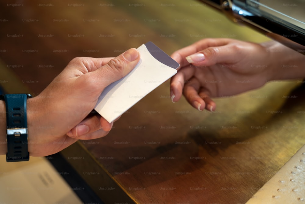 Foto recortada de un recepcionista masculino en el mostrador dando una tarjeta de acceso a una invitada