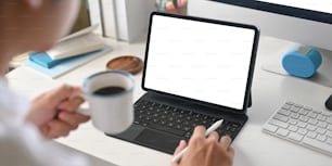 A smart man is using a white blank screen computer tablet while drinking a coffee.