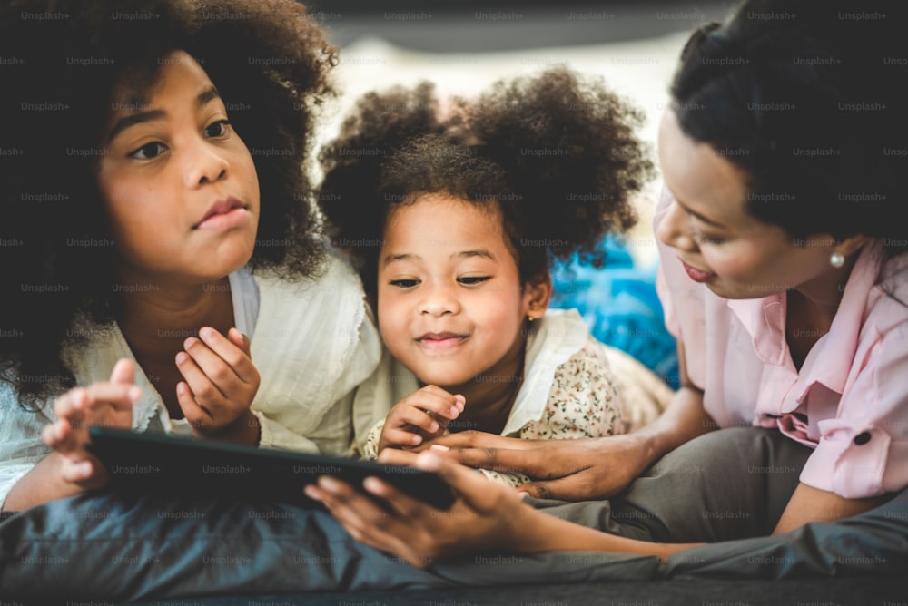 Felice famiglia africana americana che guarda il tablet sul letto a casa, il concetto di famiglie di tutte le età si sta godendo le attività in casa.