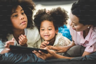 Familia africana americana feliz viendo tableta en la cama en casa, el concepto de las familias de todas las edades es disfrutar de las actividades en la casa.