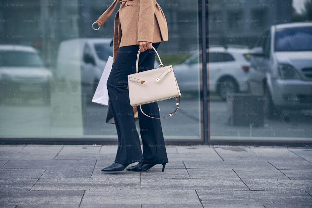 A woman kneeling on the ground holding a purse photo – Free Purse Image on  Unsplash