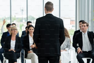 Group of business people meeting in a seminar conference . Audience listening to instructor in employee education training session . Office worker community summit forum with expert speaker .