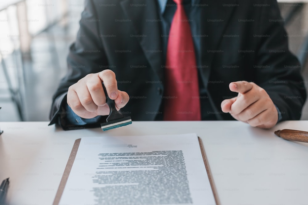 Businessman stamping with approved stamp on document at meeting.