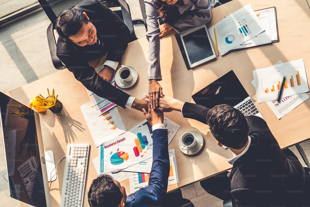 Happy business people celebrate teamwork success together with joy at office table shot from top view . Young businessman and businesswoman workers express cheerful victory showing unity and support .