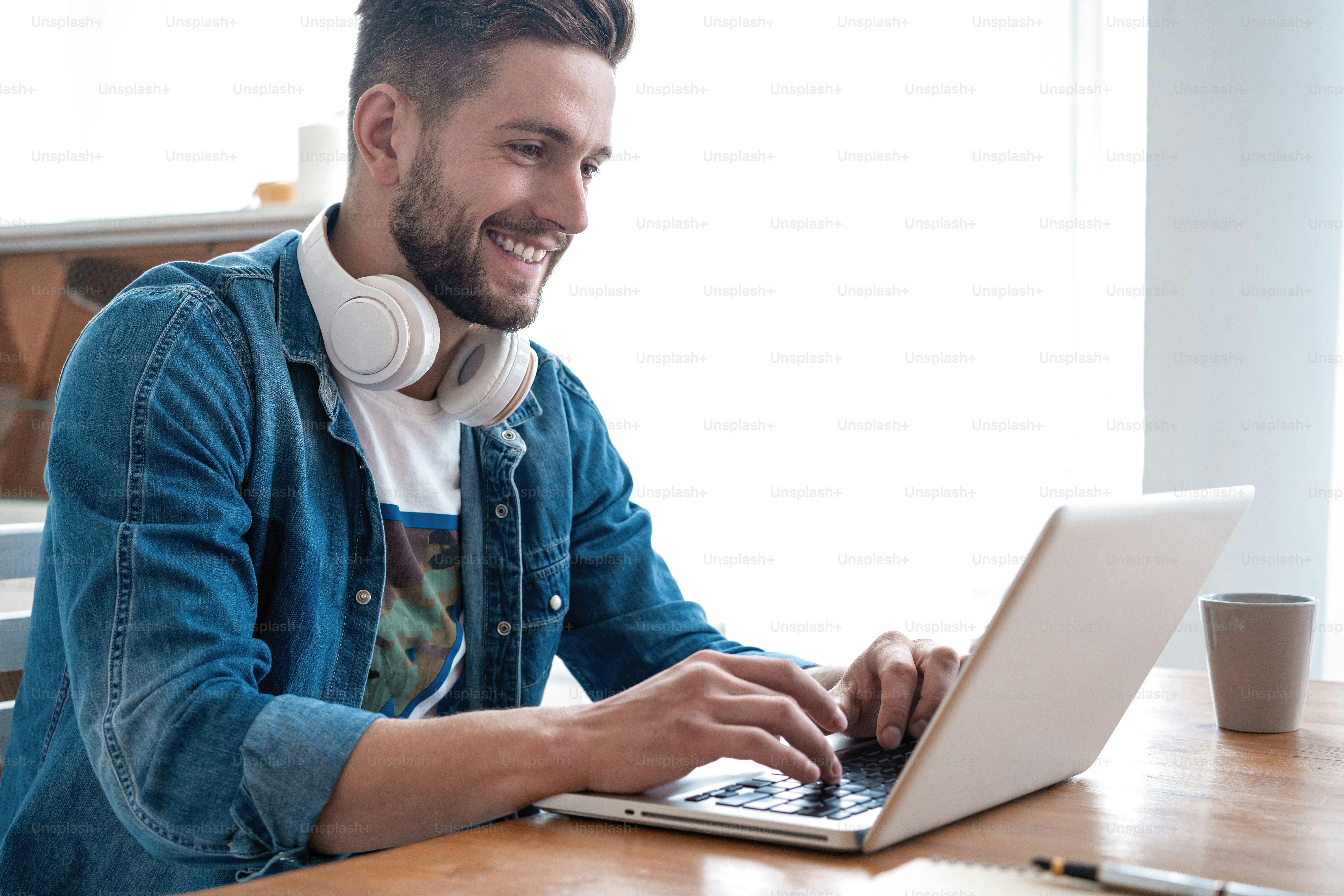 Blogger yang ceria. Desainer pria modern tampan bekerja di laptop online, menggunakan internet di rumah