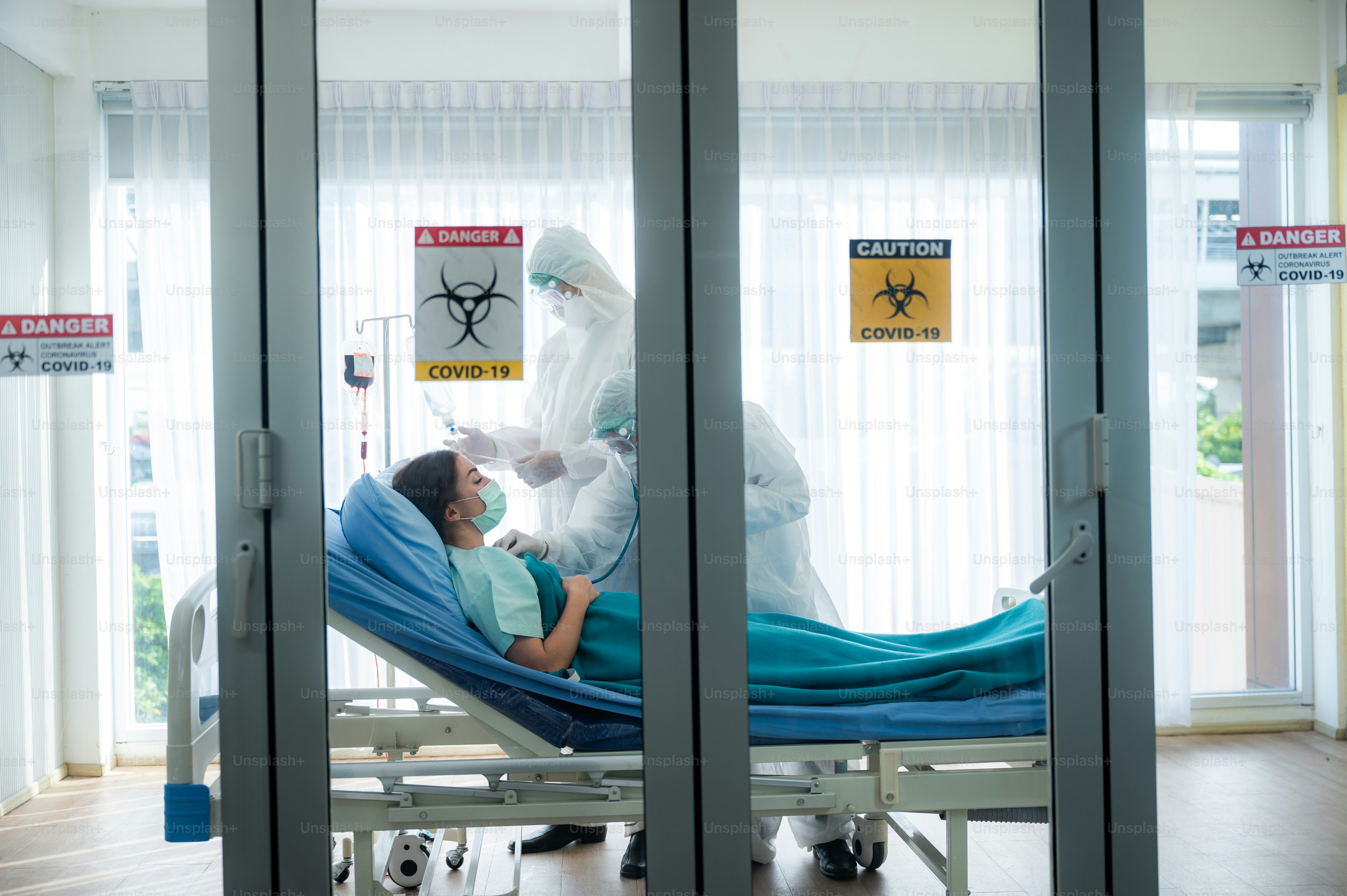 virus control experts doctor in PPE suit working for disease treatment with coronavirus COVID-19 infected patient people in hospital quarantine negative pressure room, outbreak alert sign
