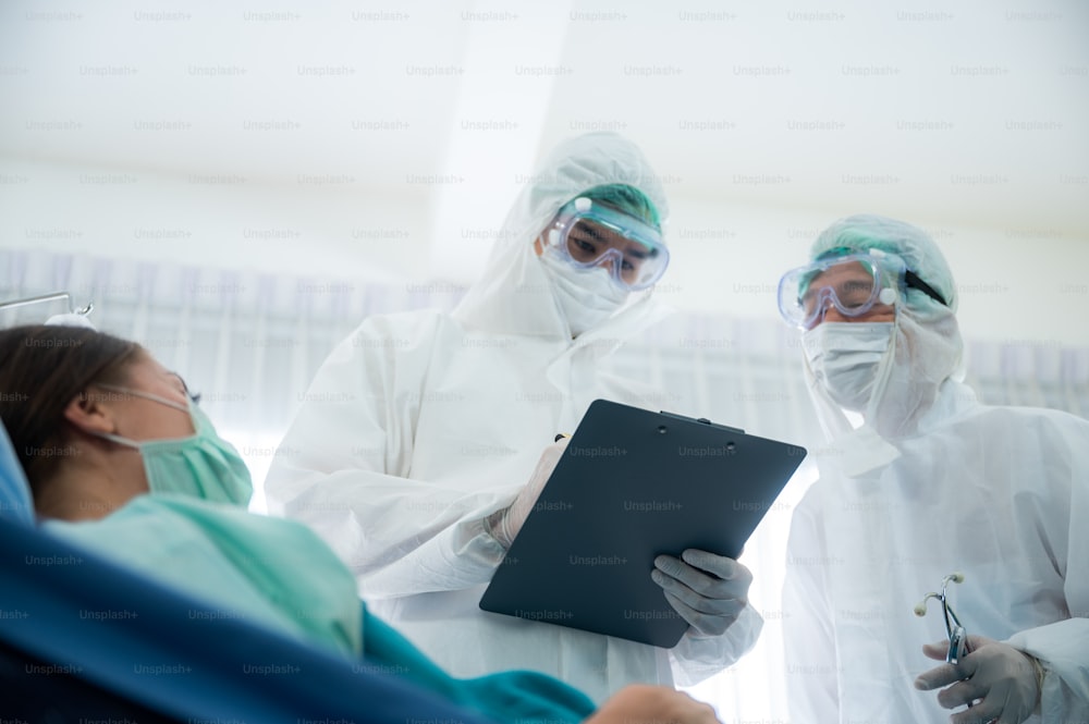 コロナウイルスの病気の治療のために働くウイルス制御の専門家の医師COVID-19に感染した患者、病院の検疫陰圧室の人々、PPEスーツの制服