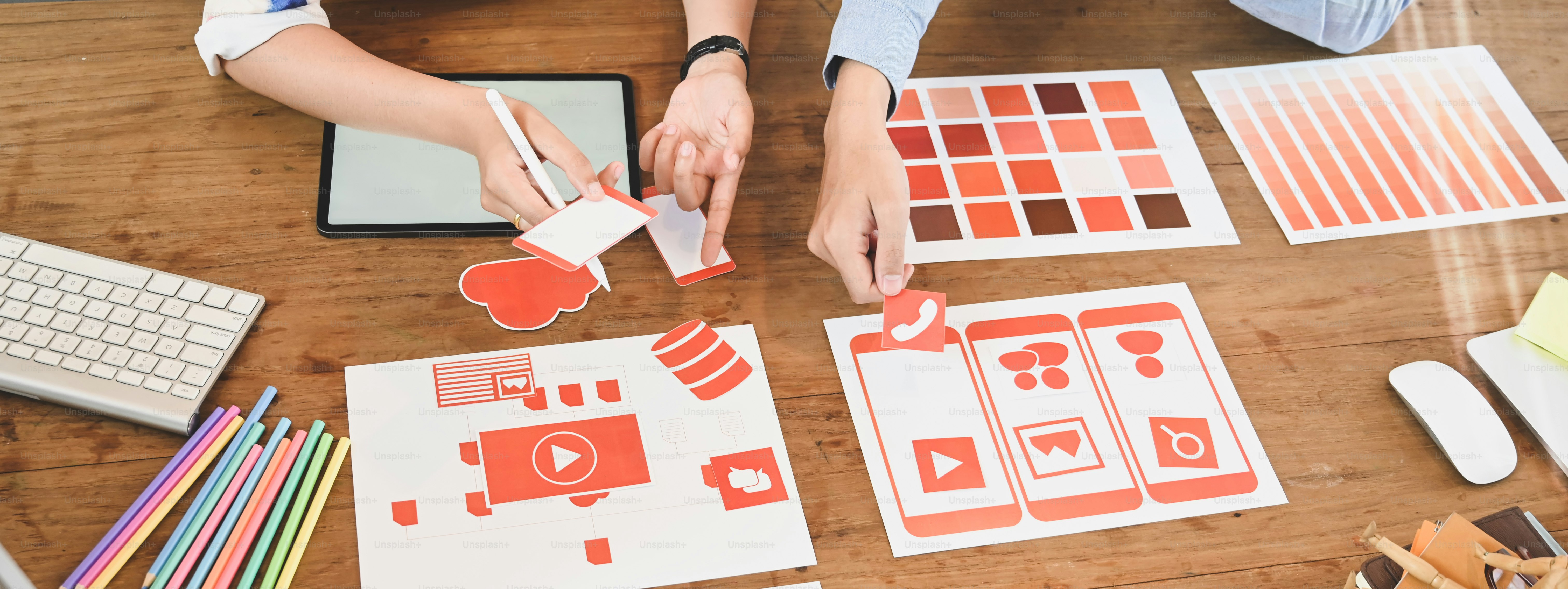 The cropped image of the UxUi developer team is working together at the wooden working desk.