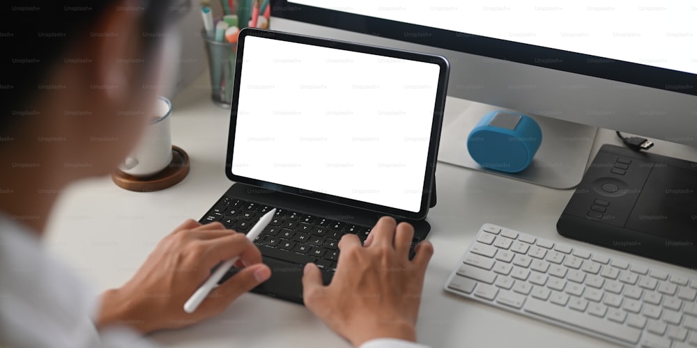 Das zugeschnittene Bild eines Geschäftsmannes verwendet ein weißes Computertablett mit leerem Bildschirm am weißen Schreibtisch.
