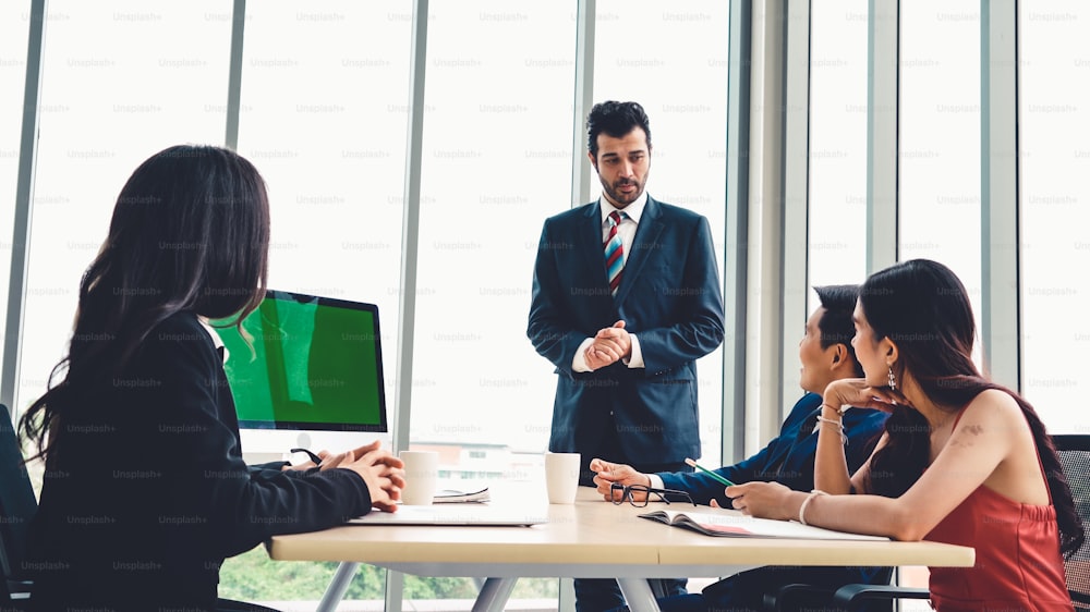 Business people in the conference room with green screen chroma key TV or computer on the office table. Diverse group of businessman and businesswoman in meeting on video conference call .