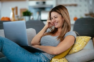 Young woman having video call on lap top. Beautiful woman talking and enjoying at home.