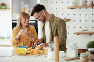 Loving couple making delicious food at home. Young couple having fun while eating a breakfast.